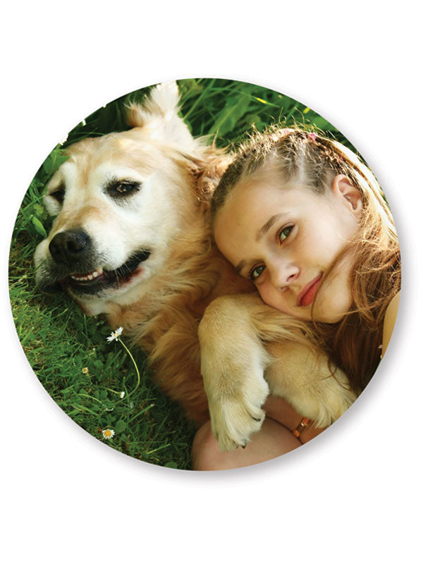 A personalized round cutting board with a photograph of a girl and a dog printed on it.